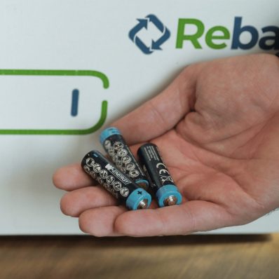 Batterien in der Hand vor der Rebat-Rücknahme-Box